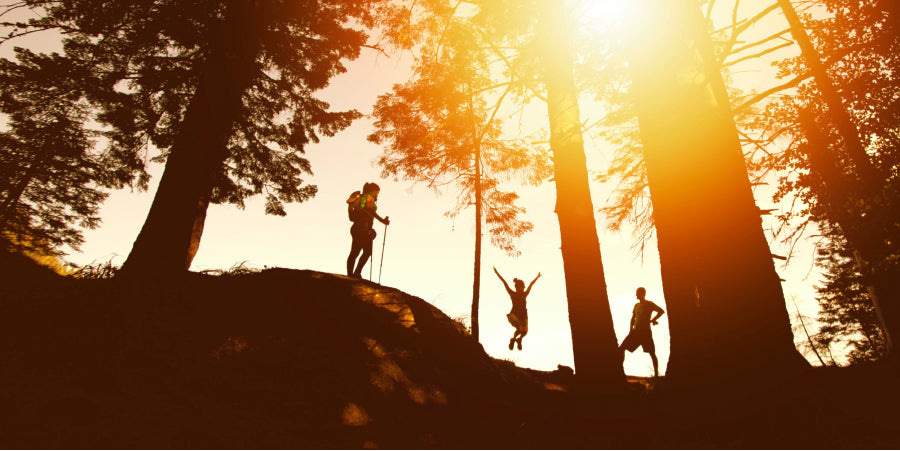 3 people hiking on hill at sunset
