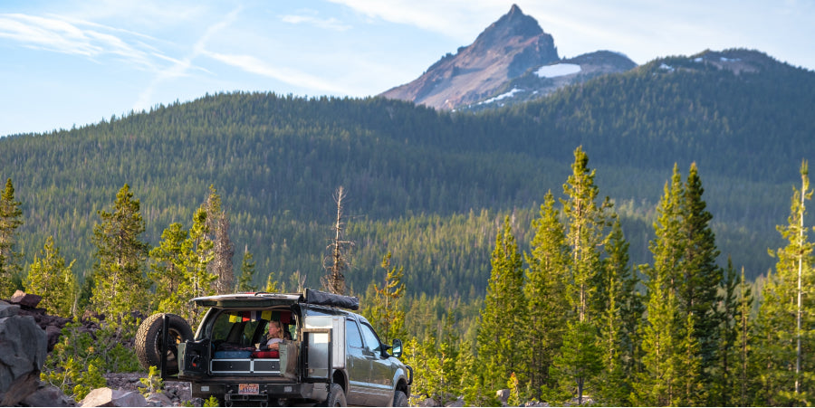 SUV in forest with mountain peak in background