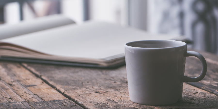 cup of coffee next to an open book