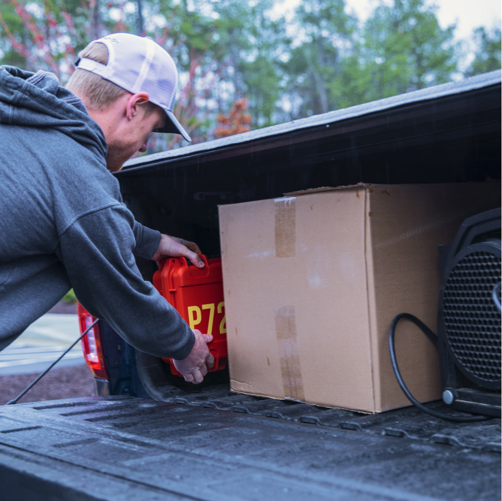 Man placing P72 disaster-proof bug out bag in the bed of a truck