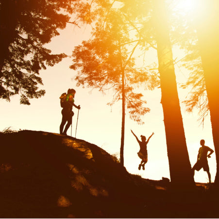 3 people hiking on hill at sunset